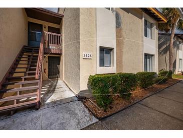 Condo exterior showcasing well-maintained landscaping, stairs, and building number for easy identification at 2625 Pine Lake Ter # B, Sarasota, FL 34237
