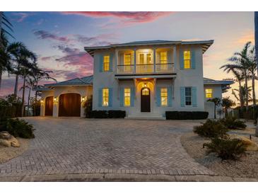 Elegant two-story home featuring a brick driveway, a balcony, and beautiful, light blue shutters at 624 N Point Dr, Holmes Beach, FL 34217