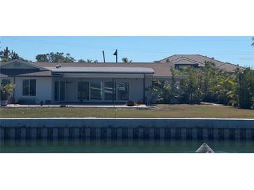 Waterfront home featuring a spacious yard with lush landscaping and an inviting patio area at 721 Emerald Harbor Dr, Longboat Key, FL 34228