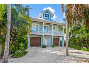 Charming two-story coastal home featuring a light blue exterior, white trim, and a welcoming front porch at 418 Magnolia Ave, Anna Maria, FL 34216