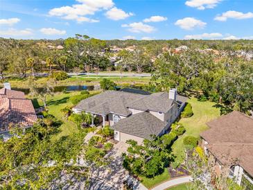 An aerial view of a home with beautiful landscaping, a pond, and mature trees, set in a suburban neighborhood at 4477 White Cedar Trl, Sarasota, FL 34238