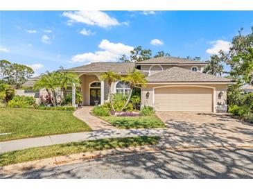 A charming home with manicured landscaping, palm trees, a brick walkway, and a two-car garage at 4477 White Cedar Trl, Sarasota, FL 34238