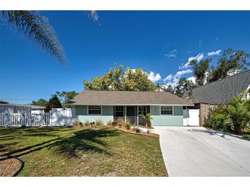 Charming single-story home featuring a well-manicured lawn, light blue exterior, and a long concrete driveway at 470 Leach St, Englewood, FL 34223