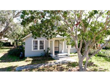 Charming single-story home featuring mature trees and a welcoming front porch with classic column supports at 617 35Th W St, Bradenton, FL 34205