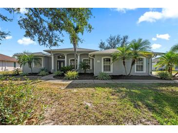 Charming single story home featuring arched windows, gray stucco, and mature landscaping at 14730 1St E Ave, Bradenton, FL 34212