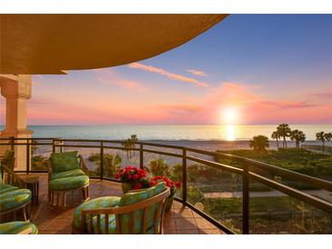 Relaxing balcony with beautiful ocean views, comfortable seating, and vibrant red flowers at sunset at 2141 Gulf Of Mexico Dr Unit # 4, Longboat Key, FL 34228