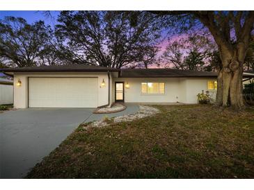 Charming home featuring a well-kept lawn, attached two-car garage, and mature trees at 2645 Belvoir Blvd, Sarasota, FL 34237