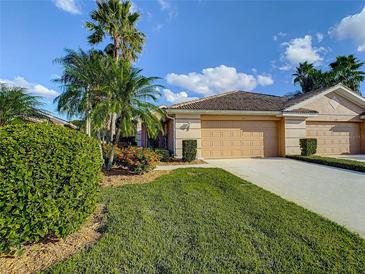 Charming single-story home featuring a well-manicured lawn, mature landscaping, and a two-car garage at 375 Fairway Isles Ln, Bradenton, FL 34212