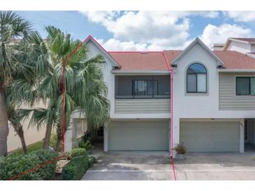 Two story townhome with attached garage and a red roof, surrounded by palm trees and lush landscaping at 625 Duchess Blvd, Dunedin, FL 34698