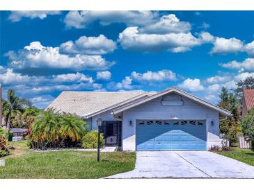 Charming one-story home with light blue garage door, mature landscaping and tile roof at 5974 San Michelle Dr, Sarasota, FL 34243