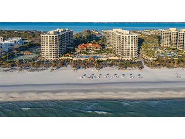 Panoramic aerial view showcasing beachfront condos, white sand, ocean views, and pristine blue ocean water at 1241 Gulf Of Mexico Dr # 1005, Longboat Key, FL 34228