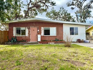 Charming, single-story brick home featuring a vibrant pink door, well-maintained lawn, and mature shade trees at 1520 2Nd E Ave, Bradenton, FL 34208