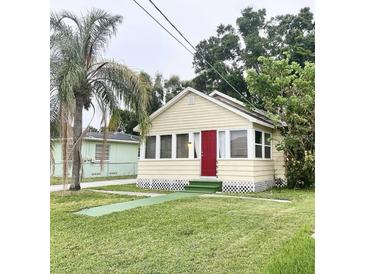 Charming, light yellow single story home featuring a well-kept lawn and a bright red front door at 3308 W Dewey St, Tampa, FL 33607