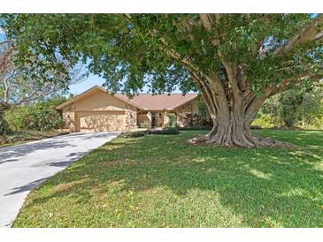 Charming single-story home with a lush green lawn and mature shade tree covering part of the house at 3970 Country View Dr, Sarasota, FL 34233