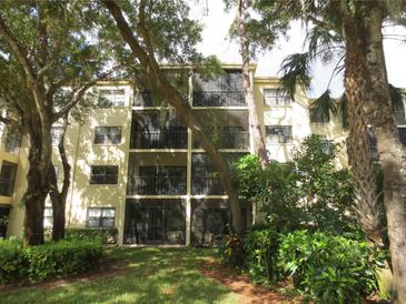 Three-story condo building featuring private screened-in patios surrounded by lush landscaping and mature trees at 425 30Th W Ave # C210, Bradenton, FL 34205