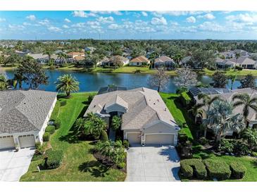 Waterfront home featuring lush landscaping, screened lanai, and beautiful lake views at 13324 Purple Finch Cir, Lakewood Ranch, FL 34202