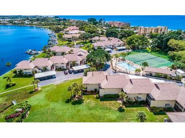 Aerial view of waterfront community showcasing lush landscaping, pool, tennis courts and boat docks at 4234 Gulf Of Mexico Dr # E2, Longboat Key, FL 34228