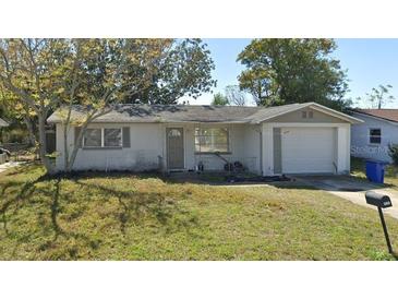Single-story home featuring an attached garage and a well-kept lawn at 3244 Fairmount Dr, Holiday, FL 34691