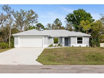 Charming single-story home with a two-car garage, neutral paint, and well-manicured landscaping at 825 Haleybury St, Port Charlotte, FL 33948