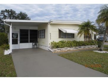 Light-yellow single-wide mobile home with a covered entryway and landscaped yard at 6405 Kilohee Ct, North Port, FL 34287