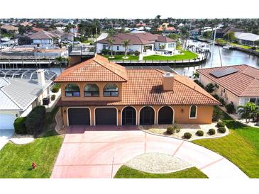 Beautiful two-story waterfront home with a tile roof, arched entryway, and well-manicured lawn at 56 Colony Point Dr, Punta Gorda, FL 33950