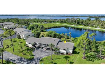 Aerial view of condo community near lake, showcasing building and landscaping at 4260 Placida Rd # 15D, Englewood, FL 34224