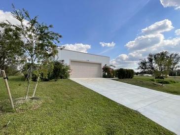 Bright home featuring a concrete driveway, well maintained lawn, and blue skies at 3140 Sweet Gum Dr, Punta Gorda, FL 33982