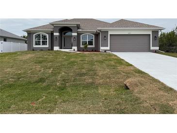 Gray house with a white garage door and a neatly landscaped lawn at 10225 Winnipeg St, Port Charlotte, FL 33981