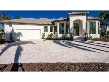 White two-story house with gray roof, paver driveway, and tropical landscaping at 435 La Sila Ct, Punta Gorda, FL 33950