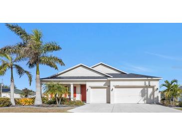 Charming single-story home with a two-car garage, complemented by lush landscaping and a vibrant red door at 25228 Nocturne Ln, Punta Gorda, FL 33983