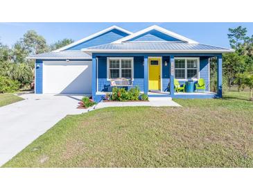 Charming blue house with a yellow door, white garage, and landscaped lawn at 28492 Royal Palm Dr, Punta Gorda, FL 33982