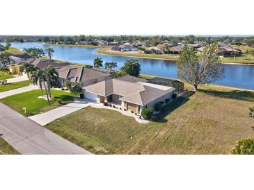 Waterfront home with a well-manicured lawn, mature palm trees, and a screened lanai overlooking the scenic water view at 2321 Sofia Ln, Punta Gorda, FL 33983