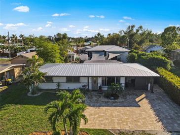 Aerial view of a single-story home with a metal roof, landscaped yard, and paved driveway at 429 W Ann St, Punta Gorda, FL 33950