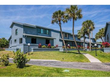 Coastal townhome showcasing blue exterior, manicured lawn, palm trees, and walkway on a sunny day at 1839 Settlers Dr # B-6, Nokomis, FL 34275