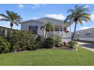 Single-story home with landscaped lawn, porch, and palm trees at 2100 Kings Hwy # 100, Port Charlotte, FL 33980