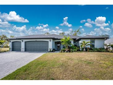 Curb appeal abounds in this 3-car garage home with a lush lawn and tropical landscaping at 25896 Prada Dr, Punta Gorda, FL 33955