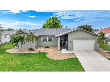 Single-story home with a green exterior, mature landscaping, and a two-car garage at 3723 Tripoli Blvd, Punta Gorda, FL 33950