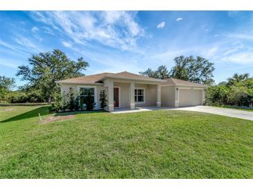 Tan house with a two-car garage, covered porch and well-manicured lawn at 6174 Alloway St, Englewood, FL 34224