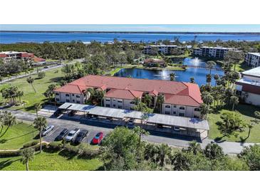 Aerial view of condo complex showcasing lake, parking, and building at 23465 Harborview Rd # 1006, Punta Gorda, FL 33980