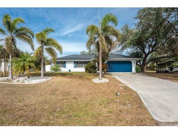 Single-story home with blue garage door and palm trees at 1236 Fleetwood Nw Dr, Port Charlotte, FL 33948
