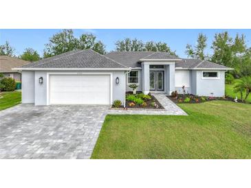 Beautiful light gray house with white garage door, landscaping, and paver driveway at 27252 Porto Nacional Dr, Punta Gorda, FL 33983