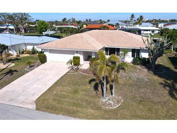 Single-story home with a large yard, driveway, and mature landscaping at 310 Capri Isles Ct, Punta Gorda, FL 33950