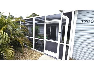 White-framed screened patio entrance with gray siding and landscaping at 3300 Loveland Blvd # 3303, Punta Gorda, FL 33980