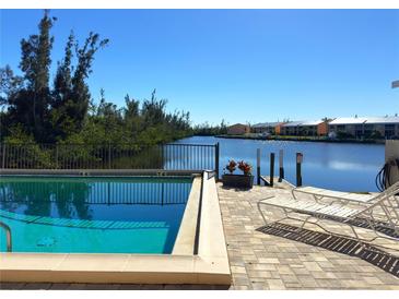 Community pool with canal view and lounge chairs at 1217 Aqui Esta Dr # 5, Punta Gorda, FL 33950