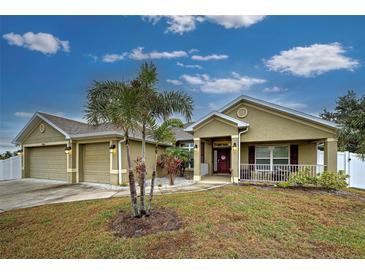 Tan house with 3-car garage, palm trees, and a covered entryway at 13536 Ainsworth Ln, Port Charlotte, FL 33981