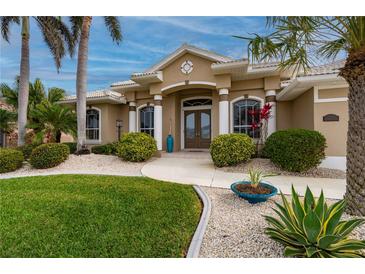 Tan house with double doors, palm trees, and landscaped yard at 1431 Grebe Dr, Punta Gorda, FL 33950