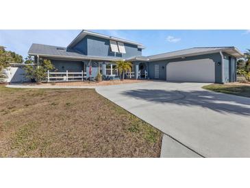 Charming blue home with a white garage door and a well-manicured lawn at 18500 Ohara Dr, Port Charlotte, FL 33948