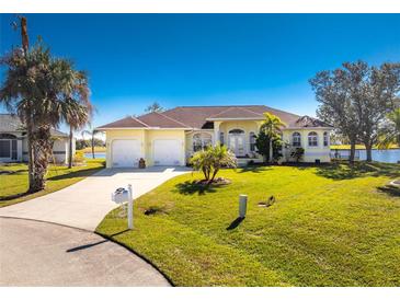 Yellow house with two-car garage and lush lawn at 24337 Contra Costa Ln, Punta Gorda, FL 33955