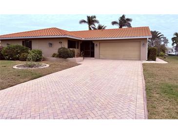 House exterior featuring a brick facade, tile roof, and landscaped yard at 310 Belvedere Ct, Punta Gorda, FL 33950