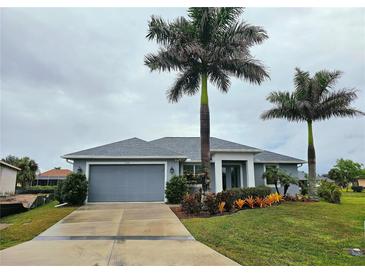 Single-story home with gray exterior, palm trees, and landscaped yard at 7342 N Ficus Tree, Punta Gorda, FL 33955